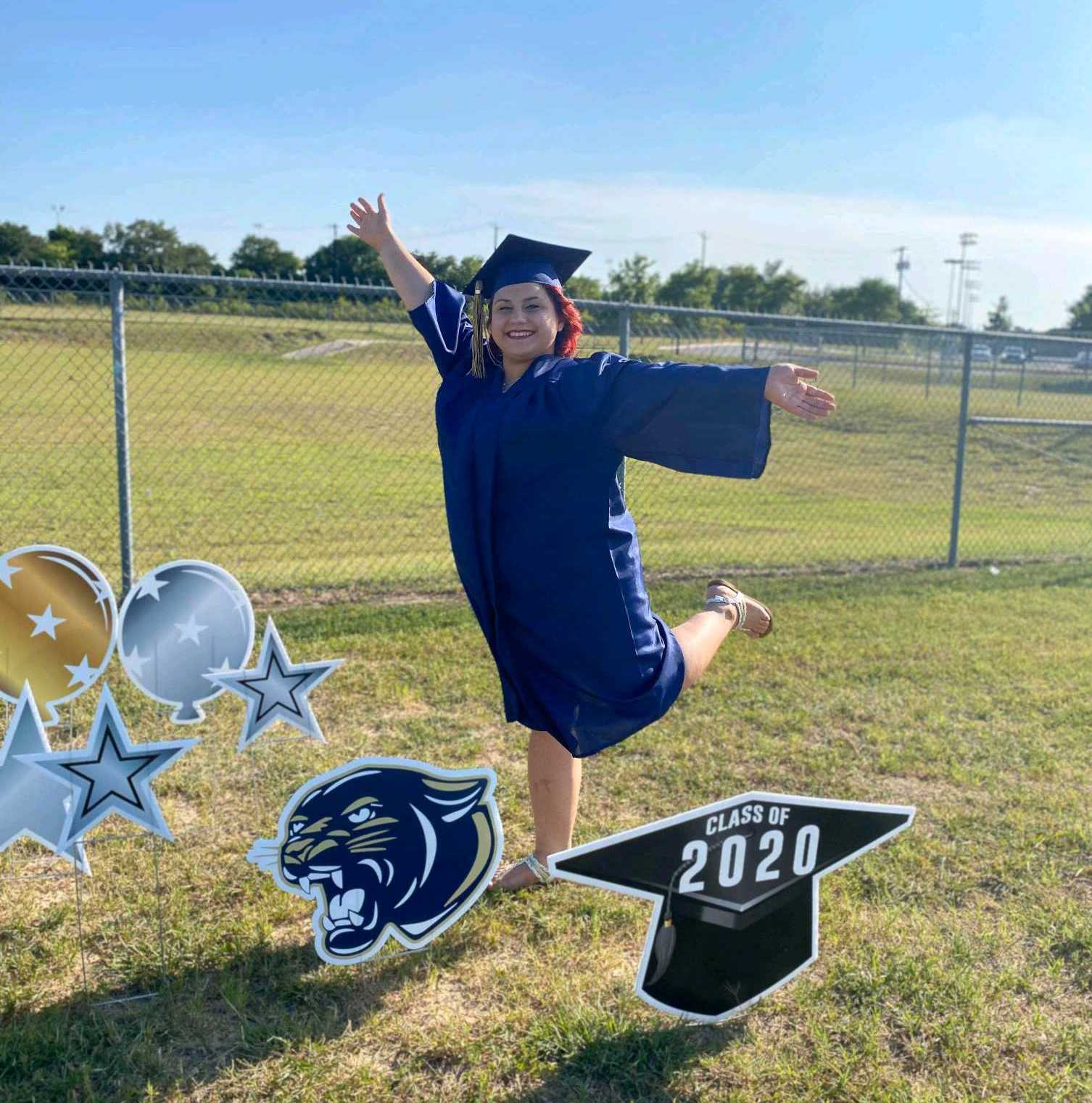 A young lady in graduation gown poses for picture