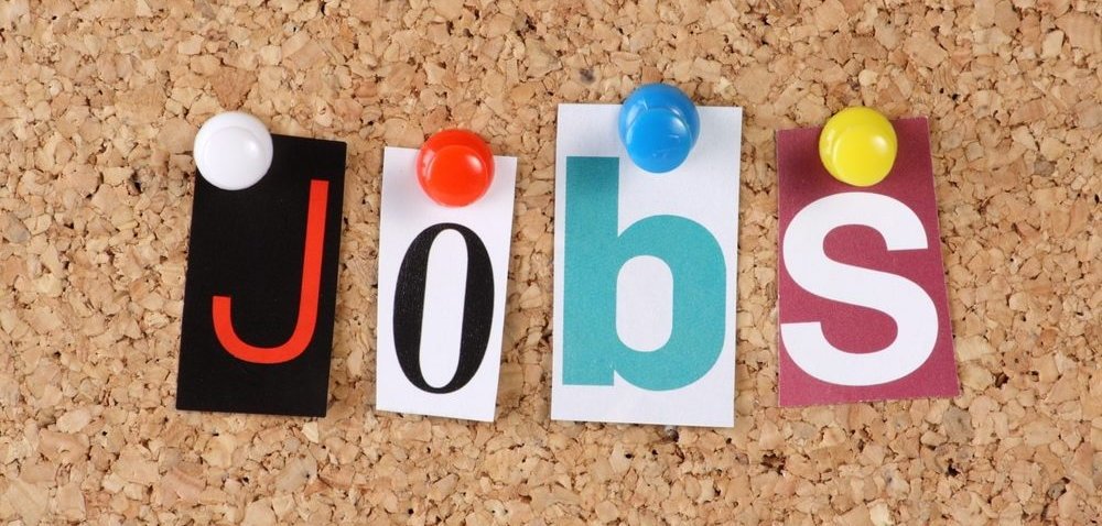 Individual letters from a magazine spell out "JOBS" pinned on a cork board