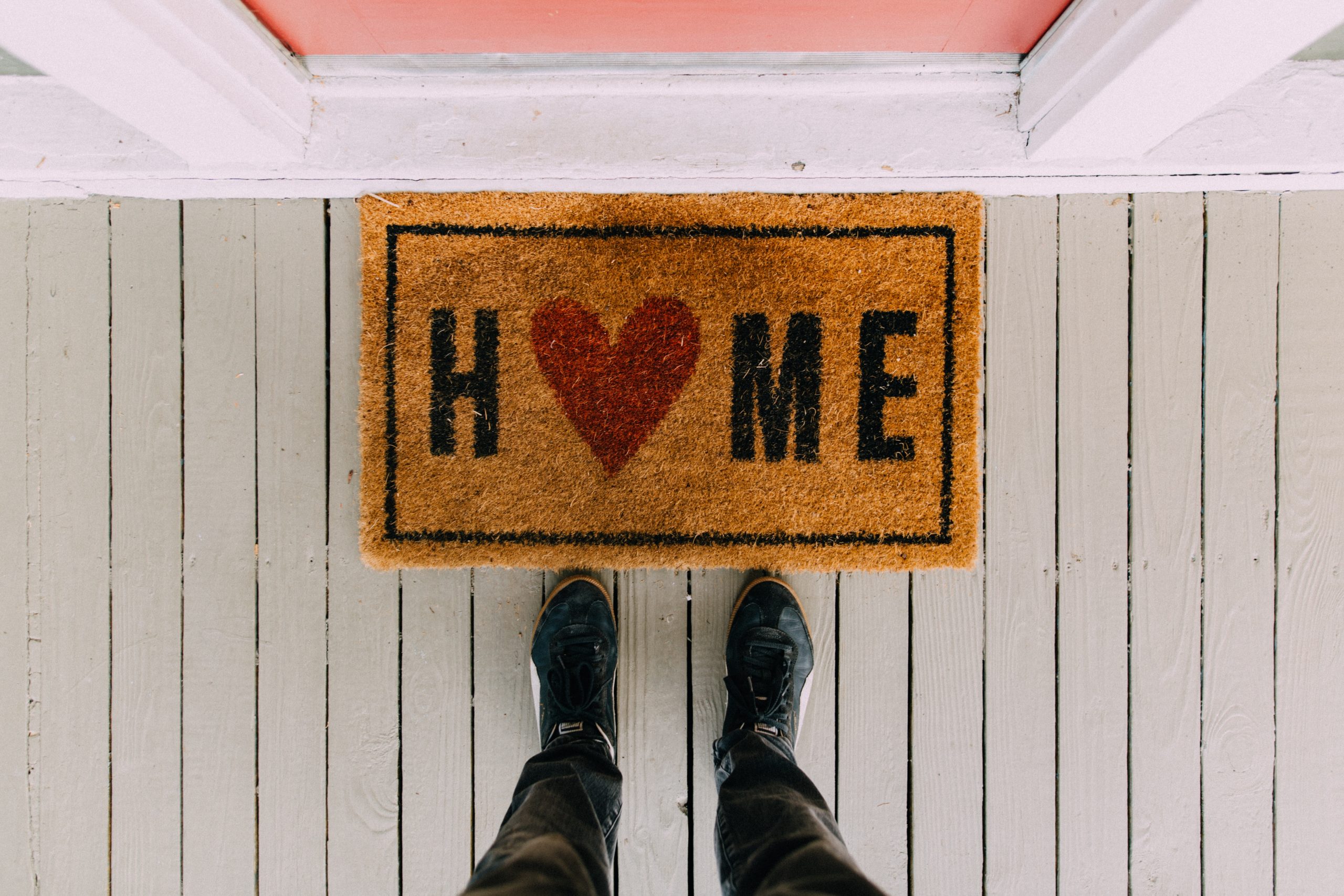 Feet at welcome mat that says "Home" with a heart