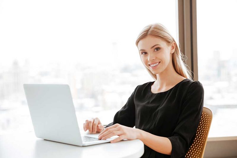 THRU Works Program to match San Antonio companies with former foster care youth workers image of happy young woman worker sitting in office while using laptop computer and typing by keyboard look at camera
